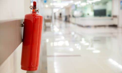 Immagine di un estintore in polvere posizionato nel corridoio di un ospedale