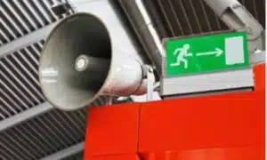 Immagine di un autoparlante con vicino la segnaletica di uscita di emergenza