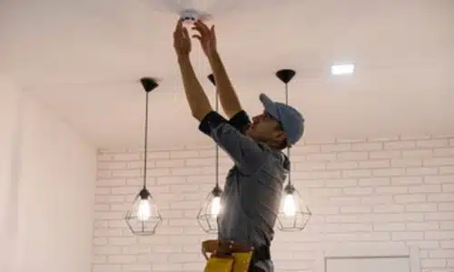 Tecnico specializzato installa rilevatore di fumo sul soffitto di ogni stanza e vicino alle vie di fuga