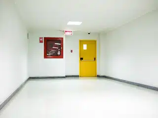 Corridoio con una porta antincendio gialla con apertura antipanico