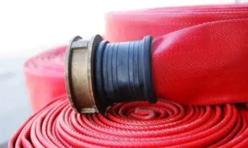immagine in primo piano di una manichetta antincendio rossa arrotolata con il bocchettone sopra