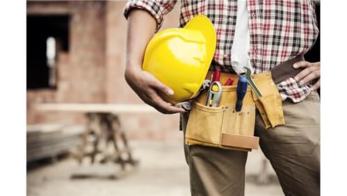 immagine di un lavoratore a mezzo busto con casco giallo in mano e legato alla vita una cintura con l'attrezzatura da lavoro