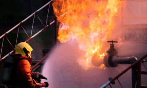 Immagine di un pompiere che estingue un incendio all'interno di un'azienda
